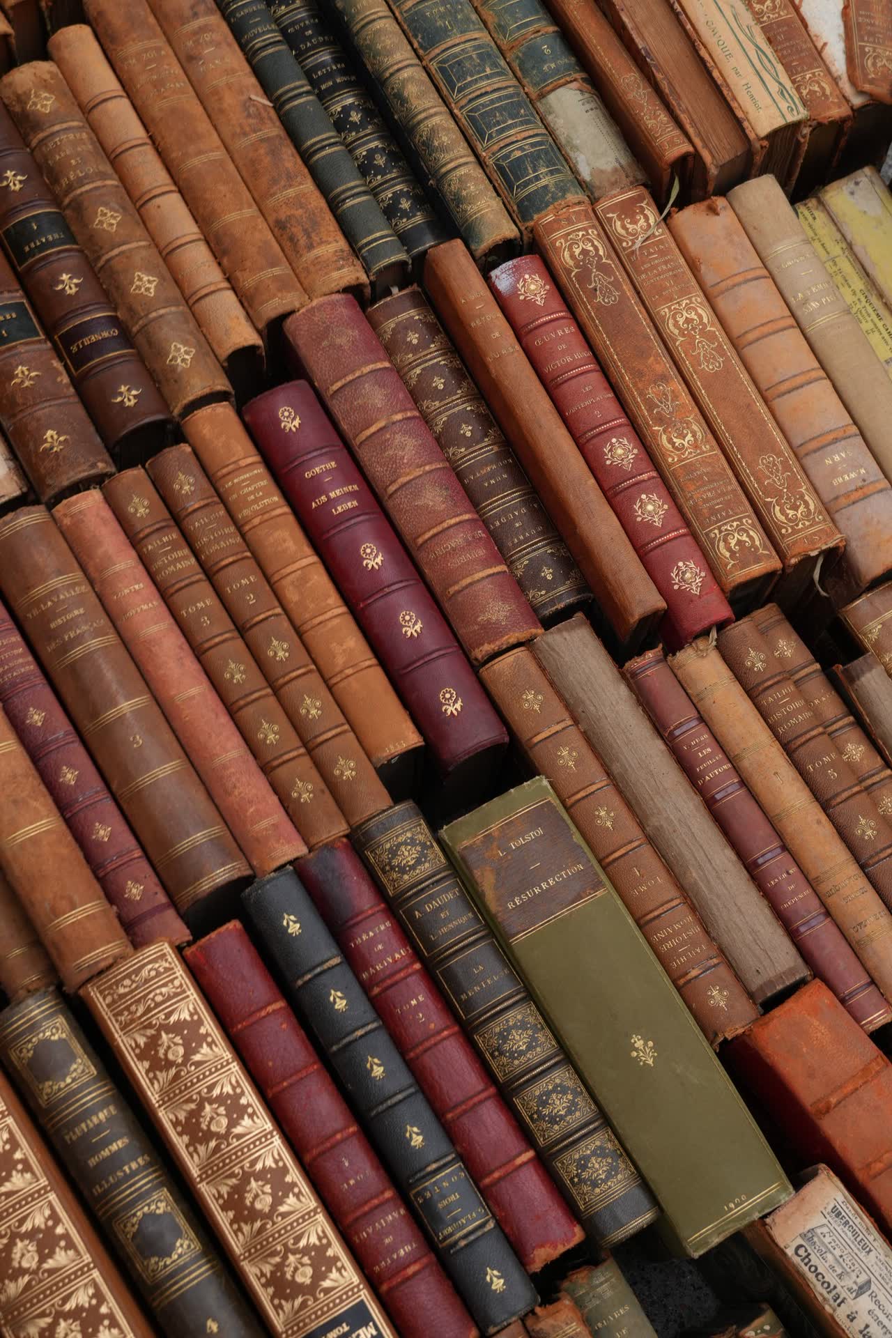 An open antique book beside reading glasses and a lantern on a wooden desk